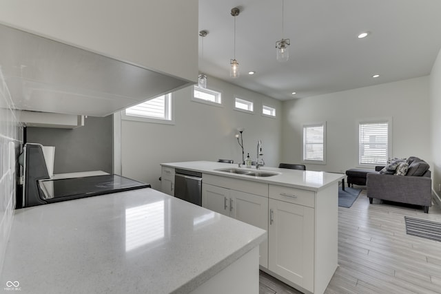 kitchen featuring white cabinets, open floor plan, hanging light fixtures, a sink, and stainless steel dishwasher