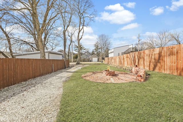 view of yard with a fenced backyard, a fire pit, and an outbuilding