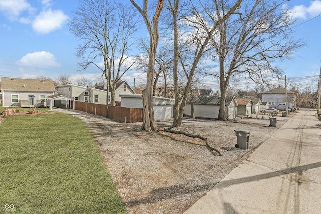 view of yard with an outdoor structure, fence, and a residential view