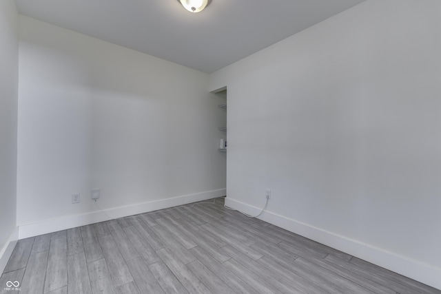 spare room with baseboards and wood finished floors