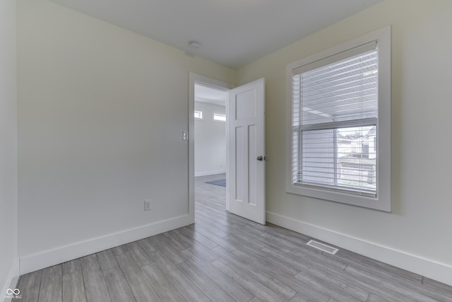 unfurnished room featuring light wood-type flooring, visible vents, and baseboards