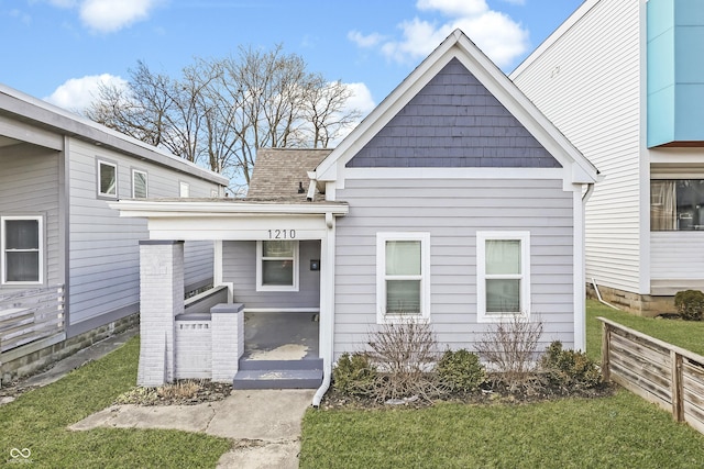 view of front of house featuring a shingled roof and a front yard