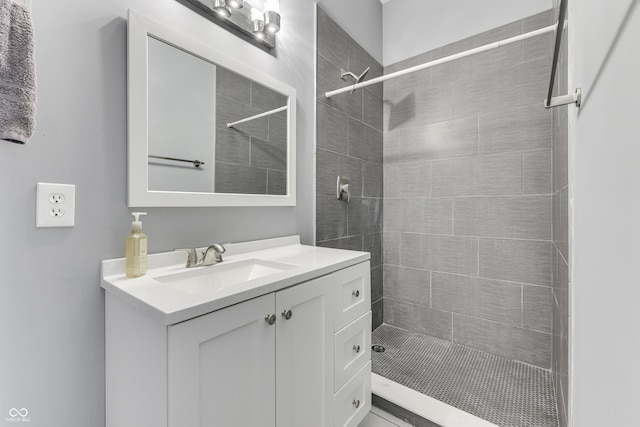 full bathroom with a tile shower and vanity