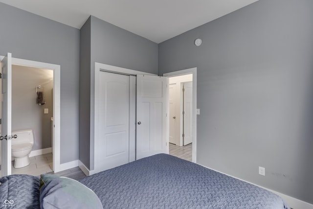 bedroom with a closet, ensuite bath, and baseboards