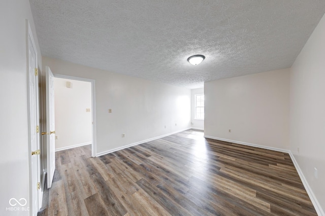 spare room featuring a textured ceiling, wood finished floors, and baseboards