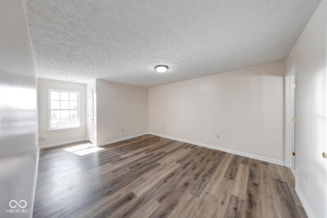 spare room featuring a textured ceiling, wood finished floors, and baseboards