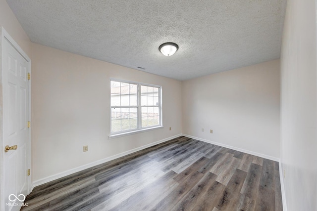 empty room with visible vents, a textured ceiling, baseboards, and wood finished floors