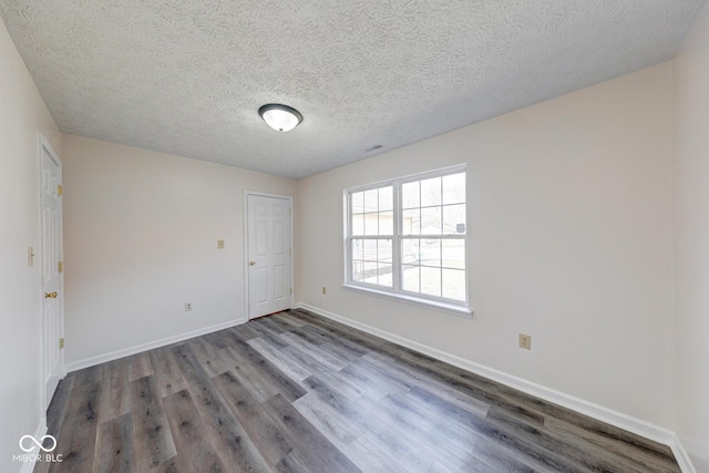 unfurnished room with a textured ceiling, baseboards, and wood finished floors