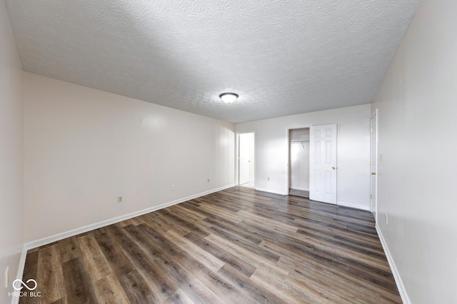 unfurnished bedroom featuring a textured ceiling, baseboards, and dark wood-style flooring