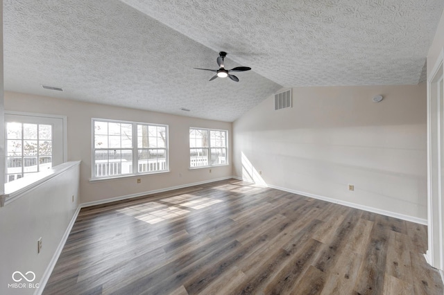 empty room with a wealth of natural light, visible vents, and wood finished floors