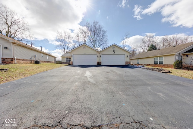 ranch-style house featuring aphalt driveway, an outdoor structure, a garage, and central AC unit