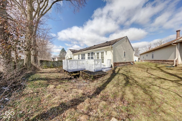 rear view of house featuring a lawn, a wooden deck, and fence