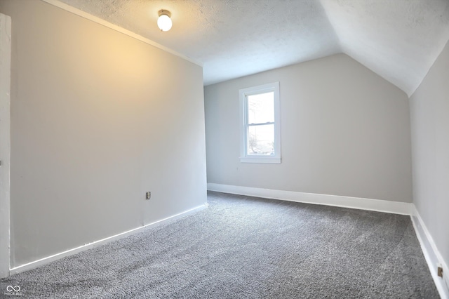 additional living space with vaulted ceiling, baseboards, dark carpet, and a textured ceiling