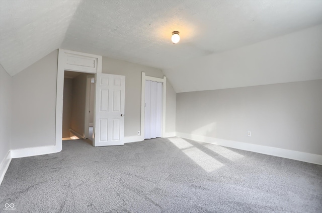 additional living space featuring lofted ceiling, carpet, baseboards, and a textured ceiling