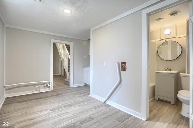 bathroom with toilet, a textured ceiling, wood finished floors, baseboards, and vanity