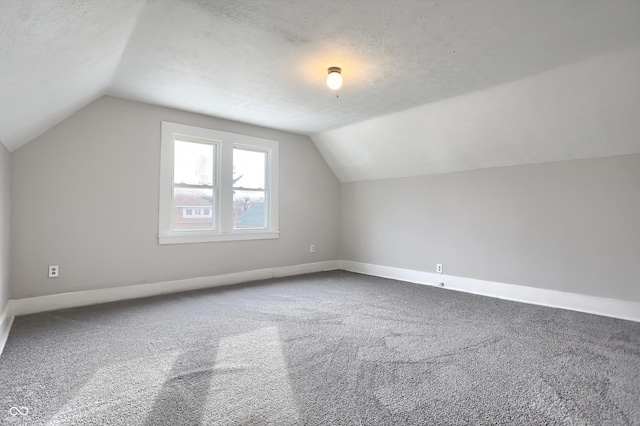 bonus room featuring baseboards, lofted ceiling, a textured ceiling, and carpet