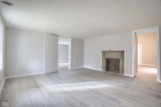 unfurnished living room featuring visible vents, baseboards, wood finished floors, and a fireplace