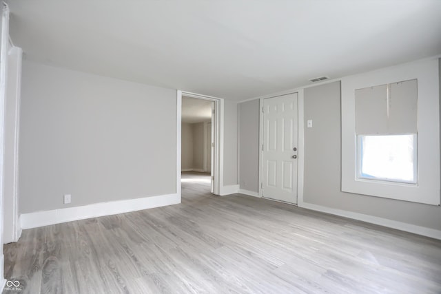 empty room with light wood-style flooring, baseboards, and visible vents