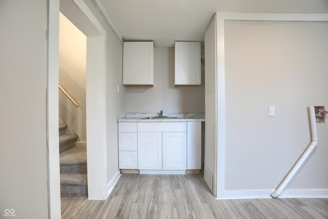 kitchen featuring a sink, light wood finished floors, white cabinetry, and light countertops