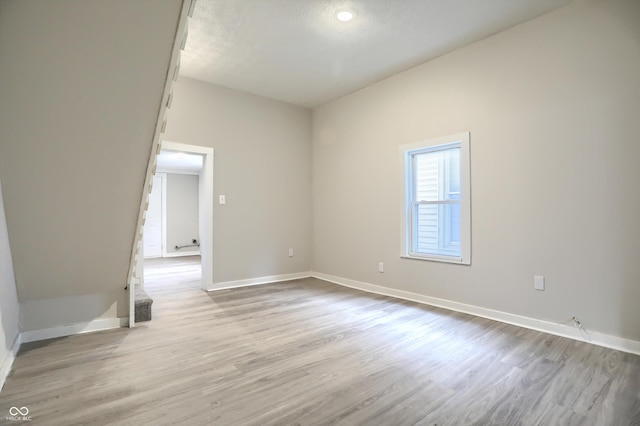 empty room featuring wood finished floors, baseboards, and a textured ceiling