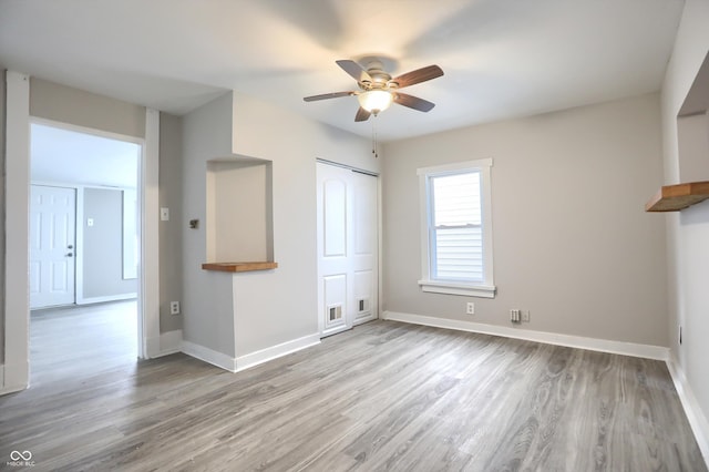 unfurnished bedroom featuring wood finished floors, visible vents, baseboards, ceiling fan, and a closet