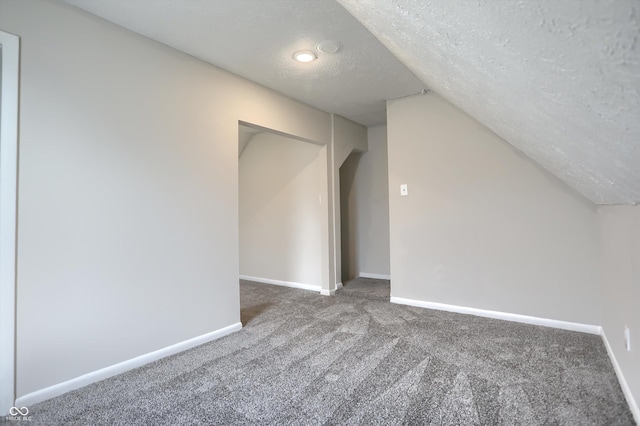 bonus room with baseboards, a textured ceiling, carpet flooring, and vaulted ceiling