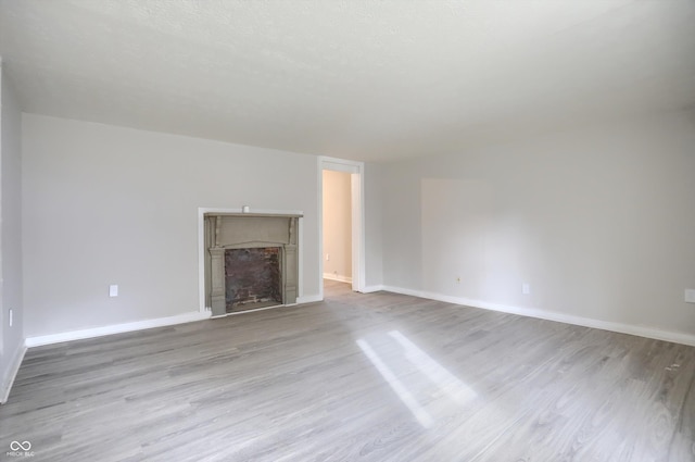 unfurnished living room with baseboards, wood finished floors, and a fireplace