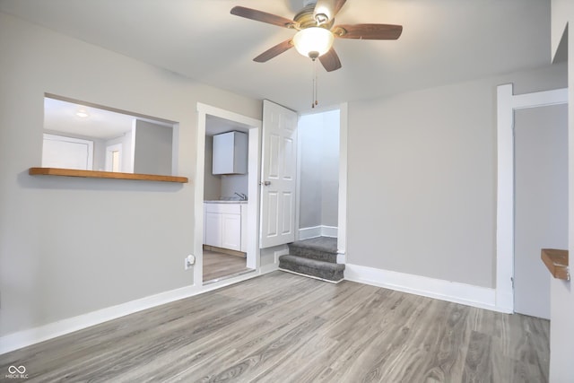 unfurnished room with a sink, baseboards, wood finished floors, and a ceiling fan