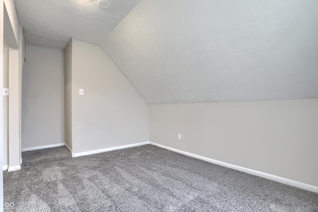 bonus room featuring vaulted ceiling, carpet flooring, baseboards, and a textured ceiling