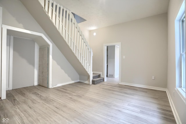 empty room featuring stairway, baseboards, and wood finished floors