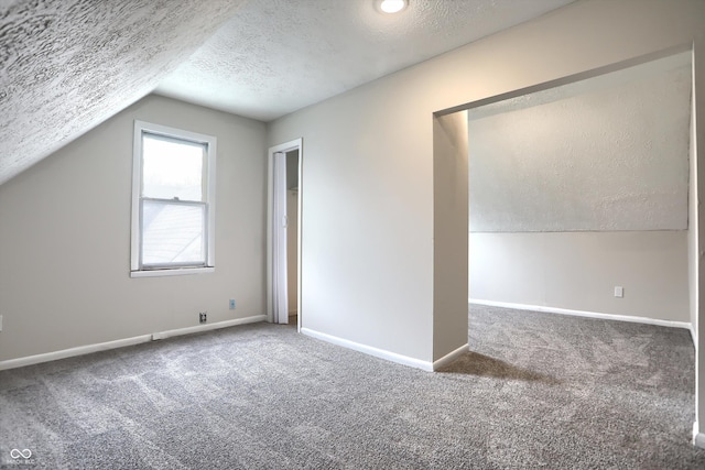 additional living space featuring carpet flooring, a textured ceiling, lofted ceiling, and baseboards