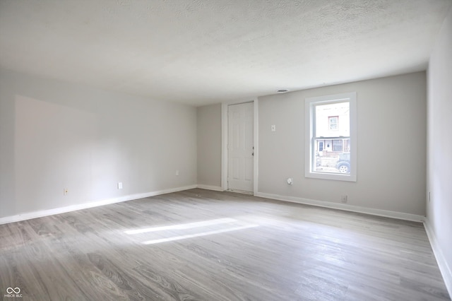 spare room featuring a textured ceiling, baseboards, and wood finished floors