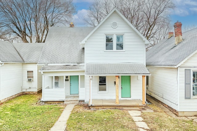 view of front facade with a front lawn, covered porch, and roof with shingles