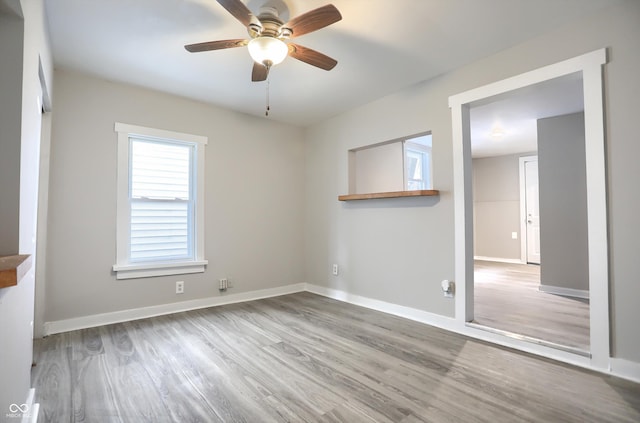 empty room featuring baseboards, wood finished floors, and a ceiling fan