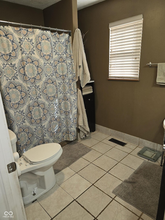 full bathroom featuring a shower with curtain, visible vents, toilet, tile patterned flooring, and baseboards