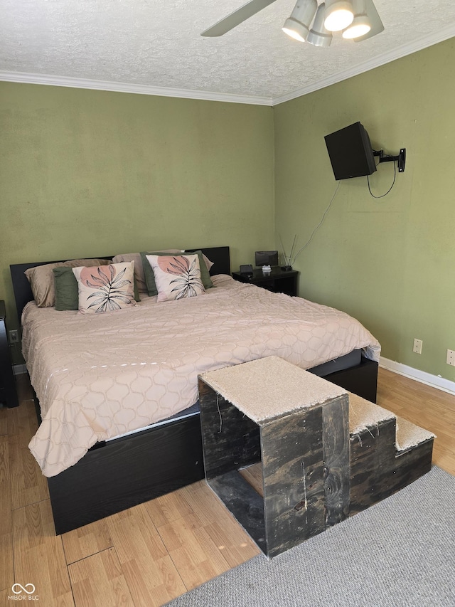 bedroom with a textured ceiling, ceiling fan, wood finished floors, baseboards, and ornamental molding