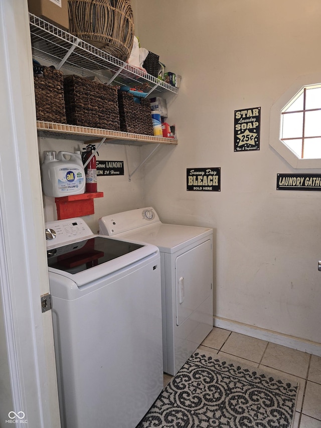 clothes washing area featuring light tile patterned floors, laundry area, baseboards, and washer and dryer