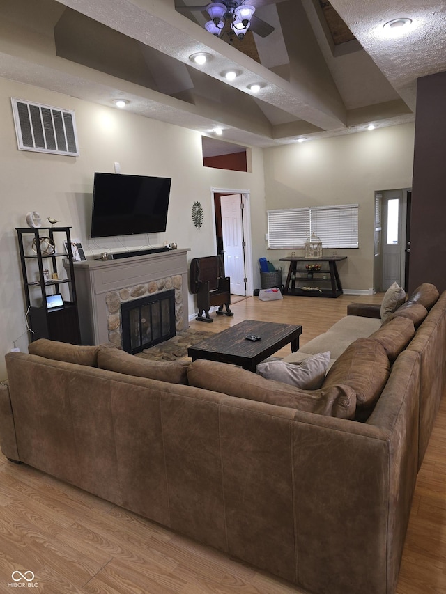 living room featuring light wood-type flooring, a fireplace, and visible vents