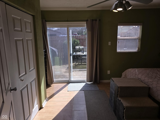 interior space featuring baseboards, ceiling fan, ornamental molding, wood finished floors, and access to outside