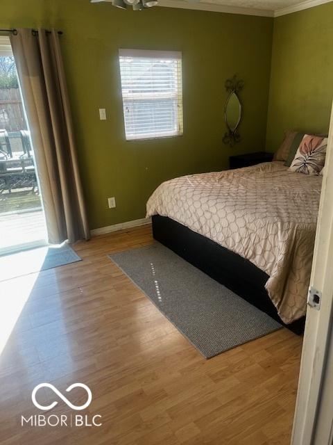 bedroom with crown molding, baseboards, and wood finished floors