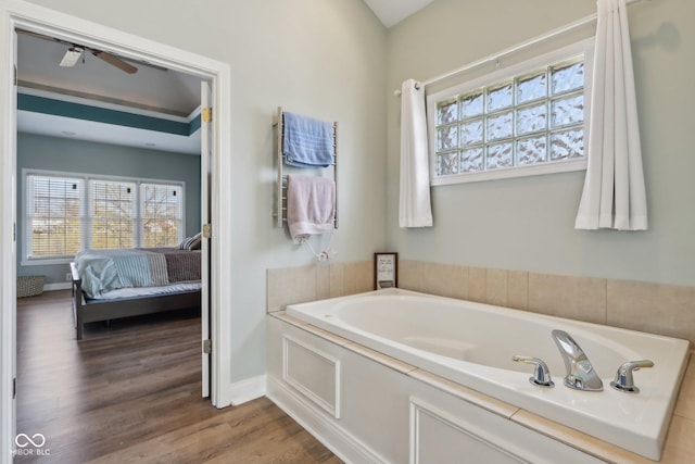 ensuite bathroom featuring ensuite bath, a bath, wood finished floors, and baseboards