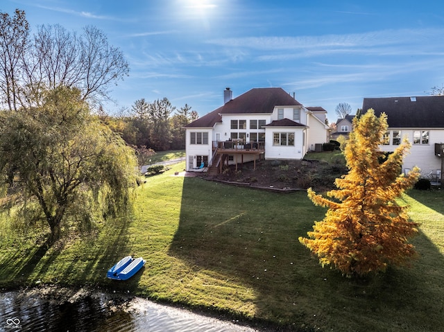 rear view of property with a wooden deck, a lawn, and a chimney