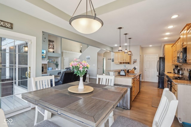 dining room featuring a glass covered fireplace, light wood-style flooring, built in shelves, and recessed lighting