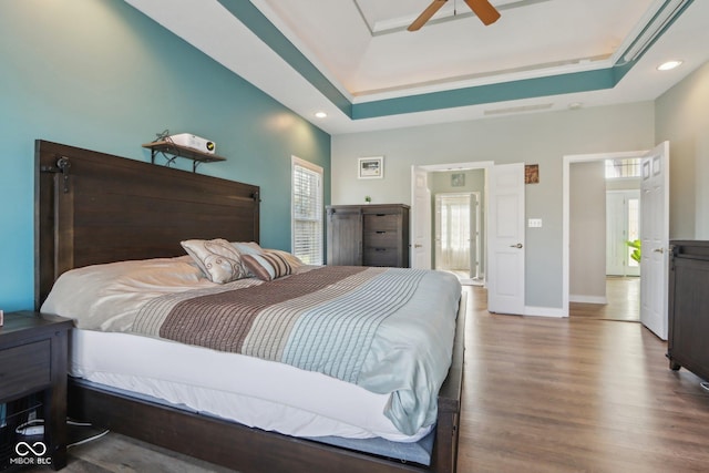 bedroom featuring baseboards, a tray ceiling, recessed lighting, wood finished floors, and a ceiling fan