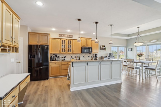 kitchen featuring a center island, glass insert cabinets, decorative backsplash, light wood-style flooring, and black fridge with ice dispenser