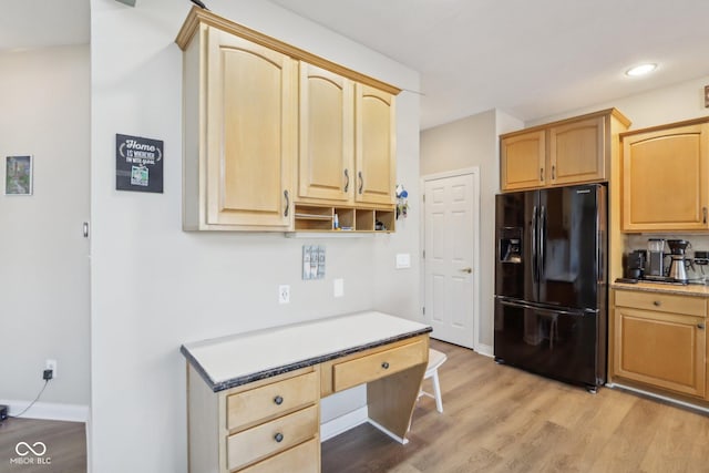 kitchen featuring light brown cabinets, built in desk, light wood finished floors, baseboards, and black refrigerator with ice dispenser