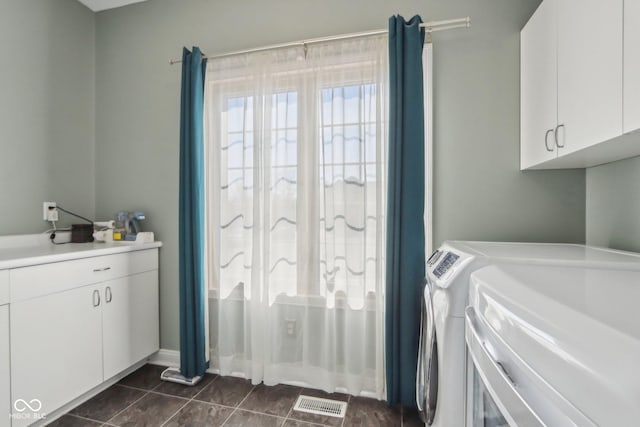 clothes washing area with cabinet space, separate washer and dryer, and dark tile patterned floors