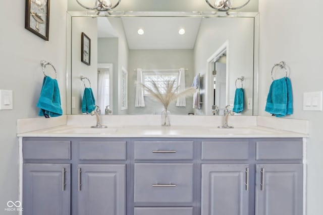 bathroom featuring double vanity, recessed lighting, and a sink