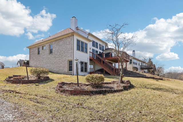 back of house featuring a deck, a chimney, stairs, and a yard