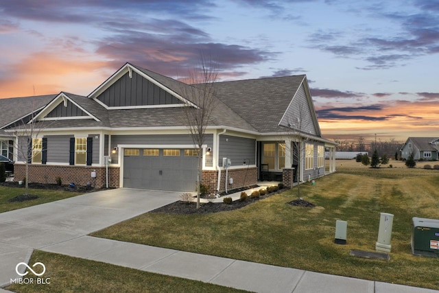 view of front facade with brick siding, a lawn, an attached garage, board and batten siding, and driveway